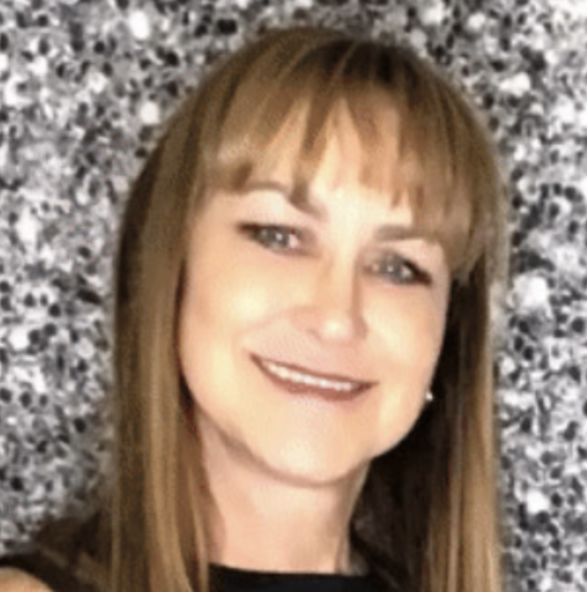 A woman with long hair and bangs smiles for the camera.