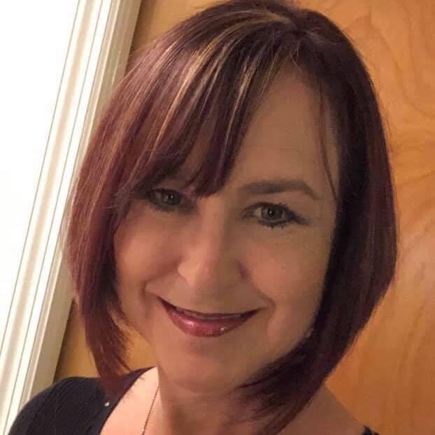 A woman with red hair and bangs smiles for the camera.