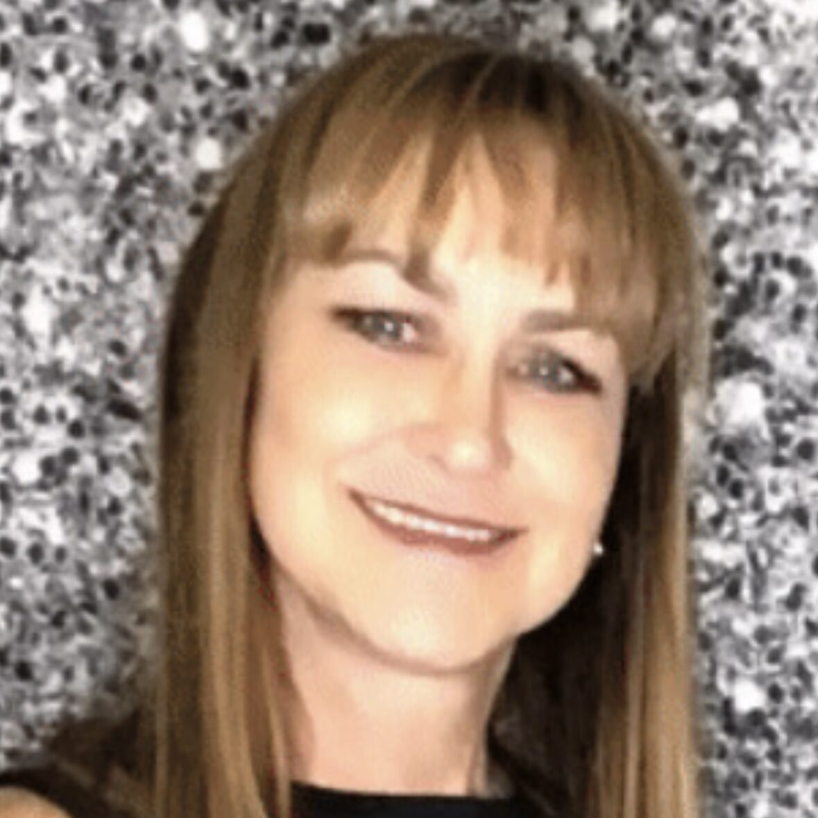 A woman with long hair and bangs smiles for the camera.